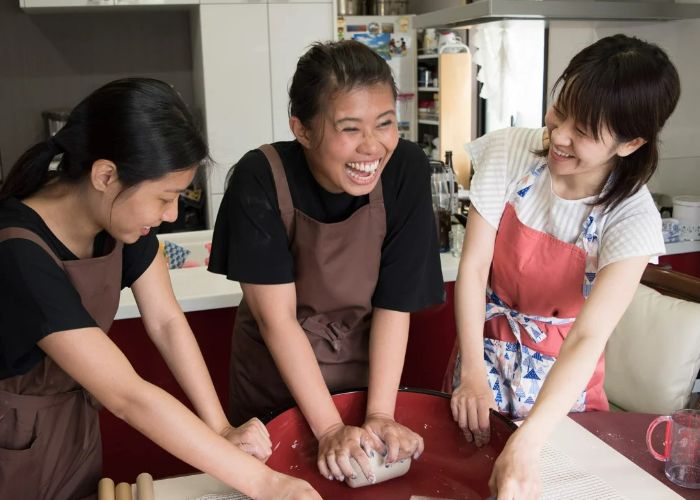 Two guests having fun kneading soba dough at a soba cooking class.